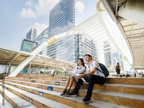 Canvas Print Wide-angle portrait of cute smiling young Asian lover tourists sitting and holdi