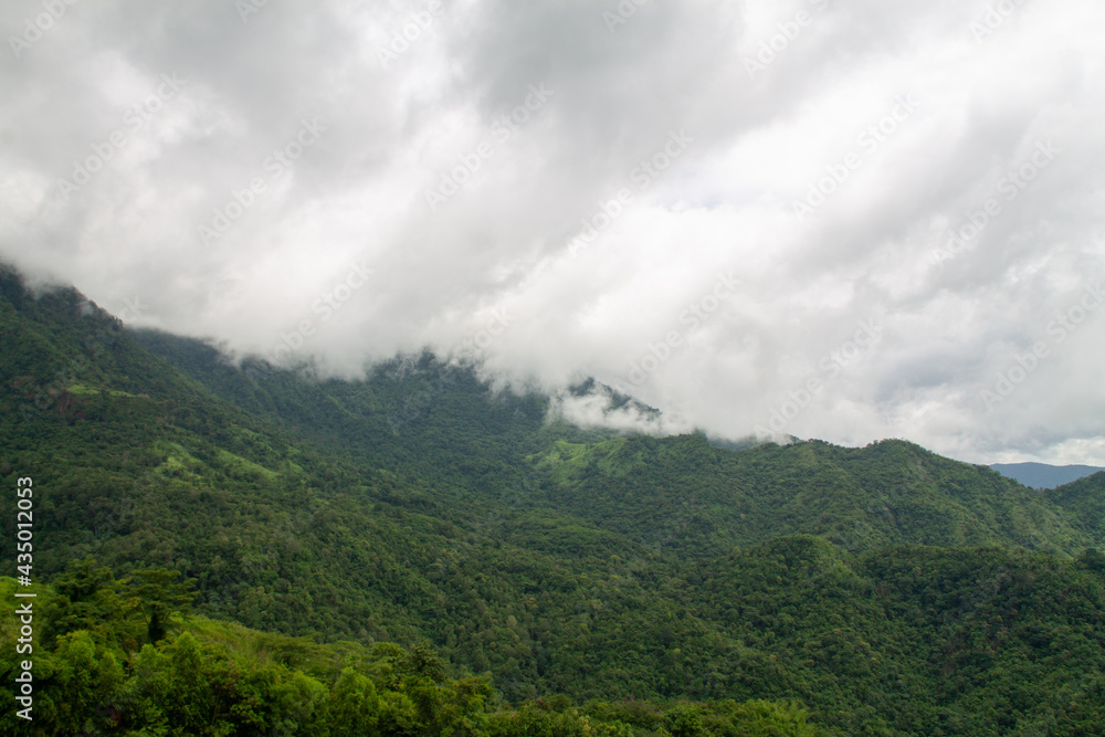 A beautiful mountain landscape with forest-covered peaks and cloudy skies.