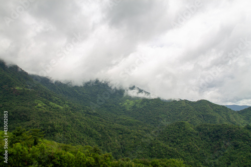 A beautiful mountain landscape with forest-covered peaks and cloudy skies. © pichai