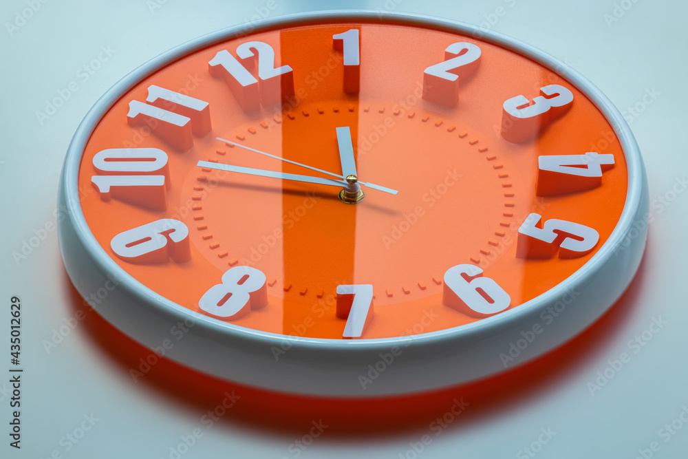 Orange clock face of a wall clock show the time. It's close to 12 o'clock. The latest report of the atomic scientist shows the doomsday clock 100 seconds to twelve. Time is running out for mankind. Orange clock face of a wall clock show the time. It's close to 12 o'clock. The latest report of the atomic scientist shows the doomsday clock 100 seconds to twelve. Time is running out for mankind.