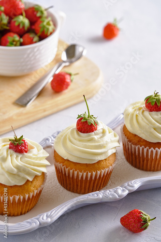 Tasty and fragrant cupcakes with strawberries and gentle cream on a white background