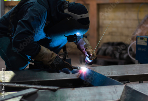 Skillful welders weld steel in the factory. Construction site metal welder.