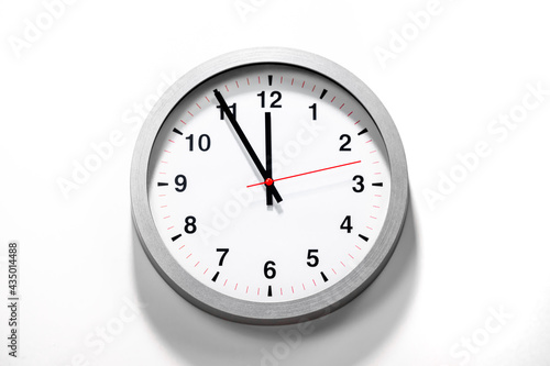 It is five to twelve, the clock is ticking. Grey Watch shows the time 5 before 12. Close up to a wall clock, with five minutes to twelve o'clock. Time is running out. White background with copy space