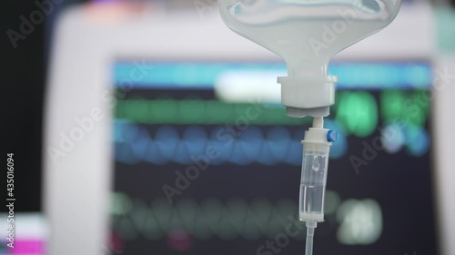 Closeup of IV loading dose in Emergency room (ER) with monitor EKG background. IV drip in hospital, Intravenous saline solution. S Cinetone like.