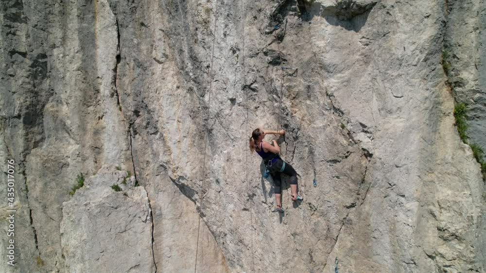 AERIAL: Drone point of view of an athletic woman learning to top rope climb in Slovenia. Unrecognizable athletic female top rope climbs in Crni Kal on a sunny spring day. Extreme outdoor sport. AERIAL: Drone point of view of an athletic woman learning to top rope climb in Slovenia. Unrecognizable athletic female top rope climbs in Crni Kal on a sunny spring day. Extreme outdoor sport.