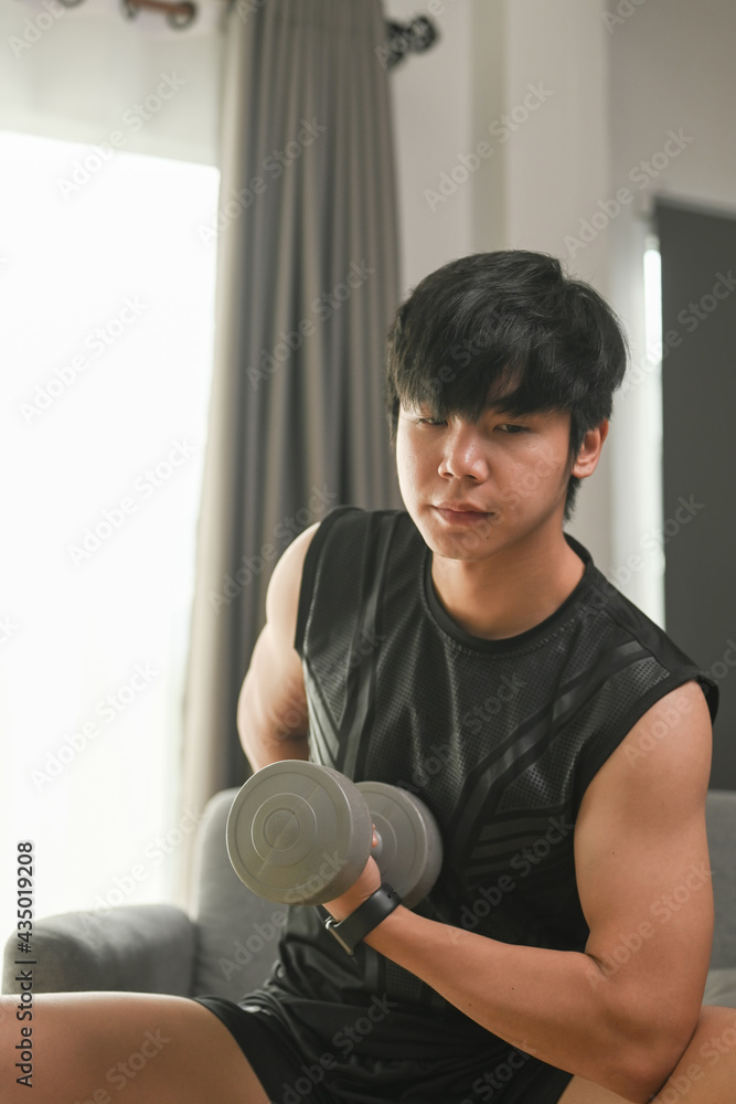 Portrait of active man exercising with dumbbells in living room. Portrait of active man exercising with dumbbells in living room.