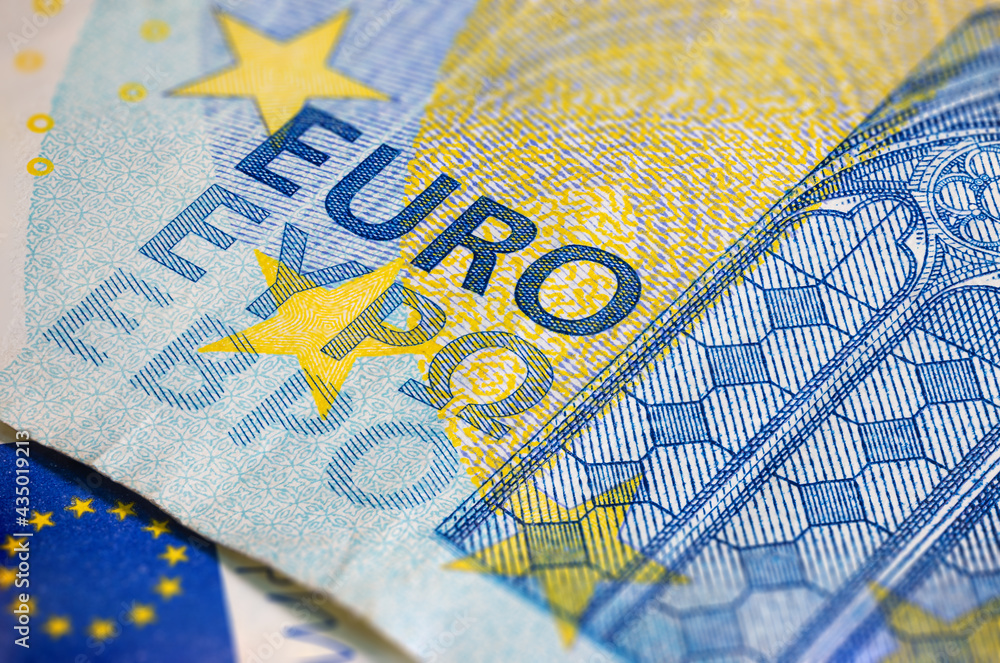 Obraz premium Fragment part of 20 euro banknote close-up with small blue details. Closeup of the twenty euro banknote, Euro currency money. Oblique detailed macro view. New Europe paper money. European Union cash