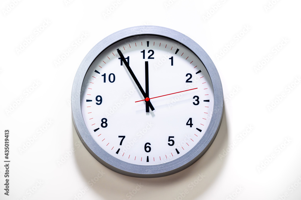 It is five to twelve, the clock is ticking. Grey Watch shows the time 5 before 12. Close up to a wall clock, with five minutes to twelve o'clock. Time is running out. White background with copy space It is five to twelve, the clock is ticking. Grey Watch shows the time 5 before 12. Close up to a wall clock, with five minutes to twelve o'clock. Time is running out. White background with copy space