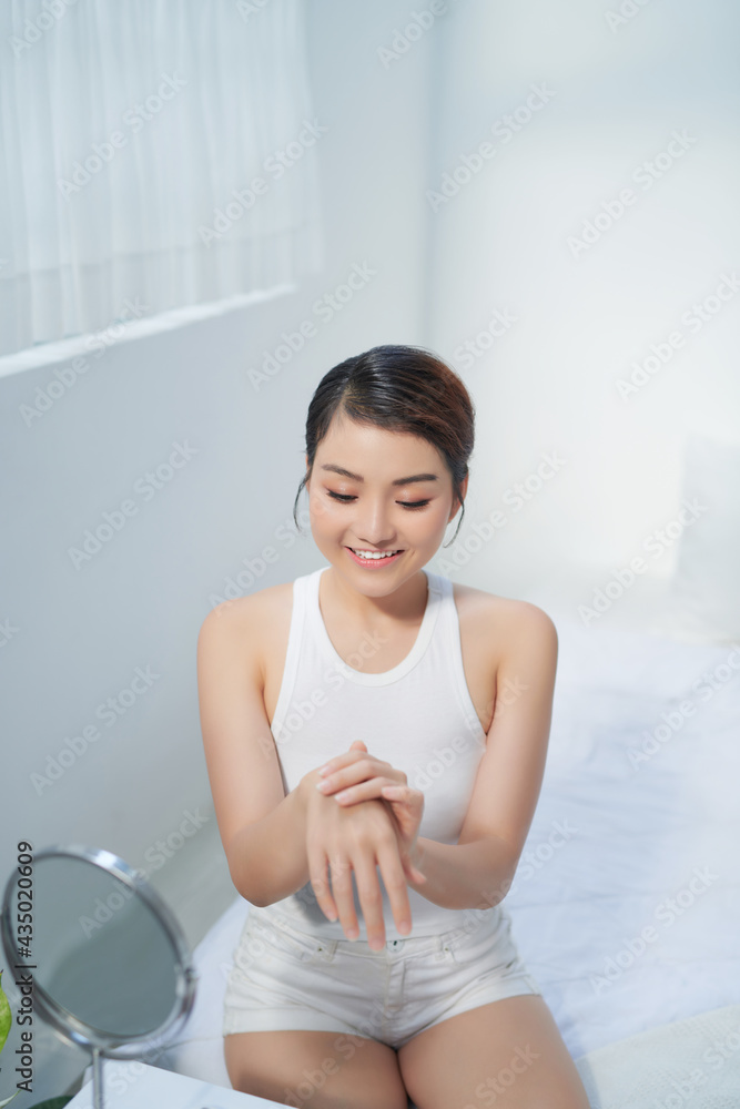 Young skin care woman applying body lotion on arm and shoulder at home Young skin care woman applying body lotion on arm and shoulder at home