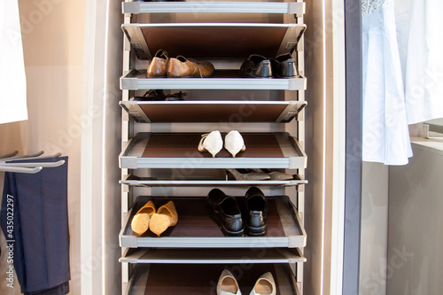 Men's and woman's shoes on the modern convenient shoes shelf in the wardrobe
