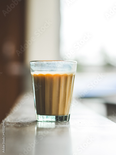 Indian chai in glass cups with metal kettle and other masalas to make the tea.