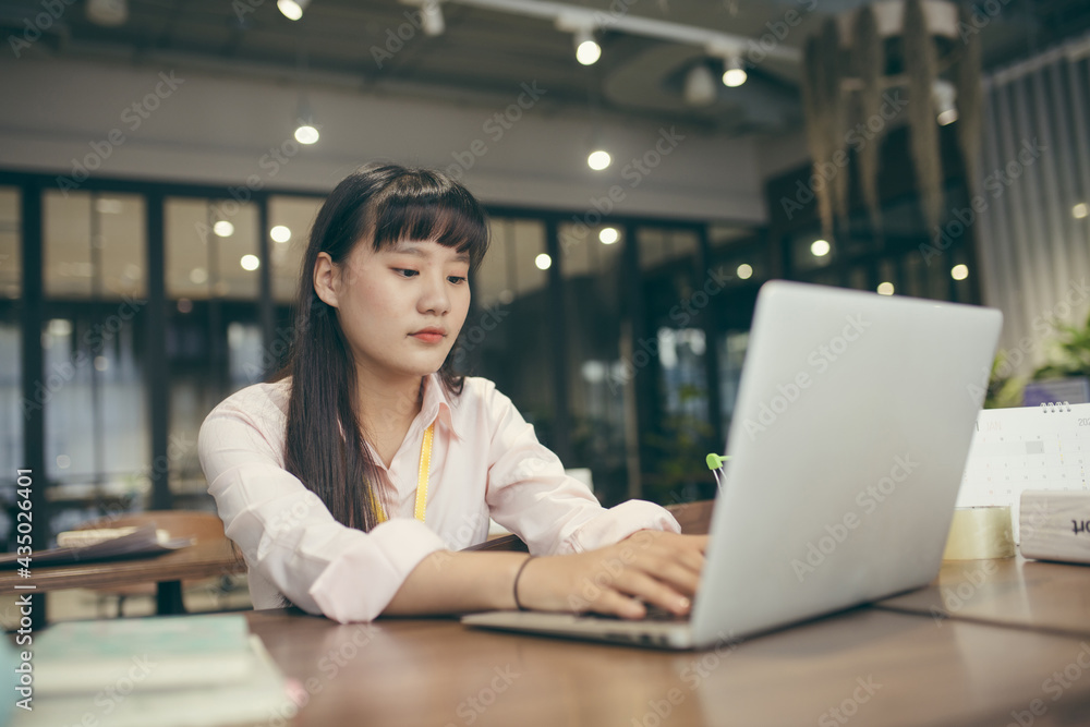 Fototapeta premium Asian young business girl working in office. Portrait of smiling pretty young business woman sitting on workplace