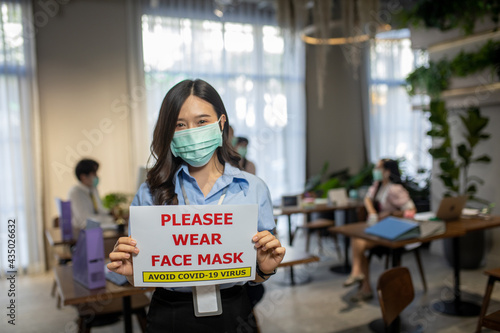 woman asian wearing a surgical mask puts an open sign warning "No Mask No Entry",