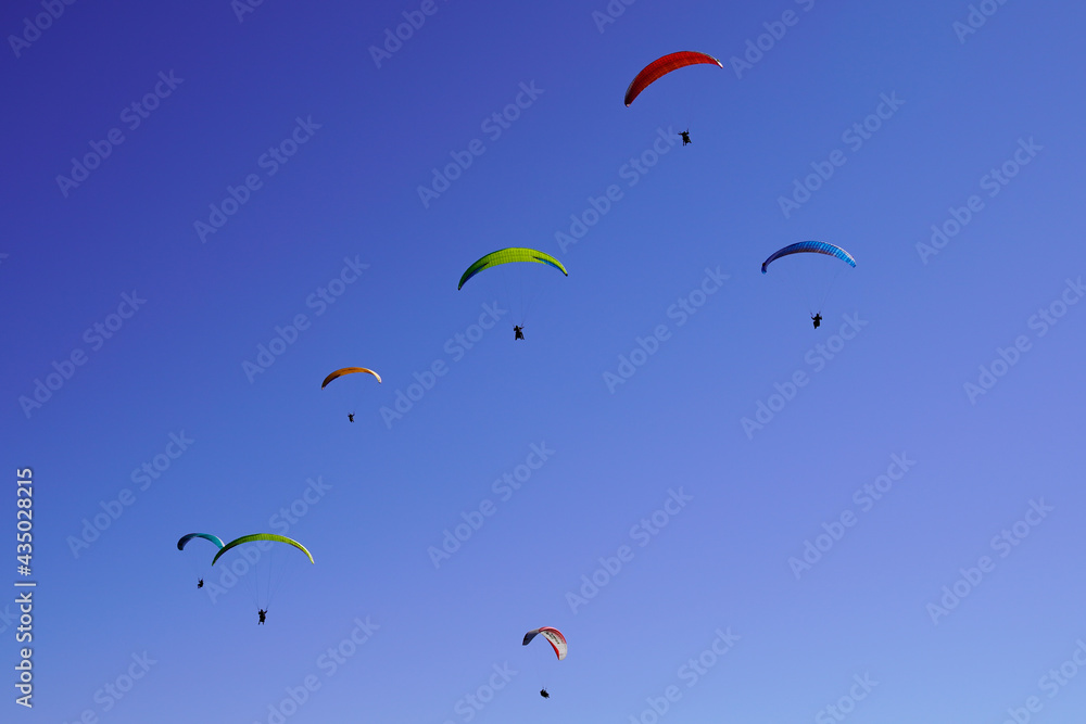 parachute paragliders enjoy a thermal updraft in Puy de Dome blue sky in Auvergne French Massif Central France parachute paragliders enjoy a thermal updraft in Puy de Dome blue sky in Auvergne French Massif Central France
