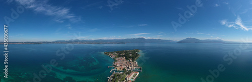 Fototapeta Naklejka Na Ścianę i Meble -  Panorama of Lake Garda. Aerial view of the island of Sirmione. Sirmione, Lake Garda, Italy. Peninsula on a mountain lake in the background of the alps. Castle on the water in Italy.