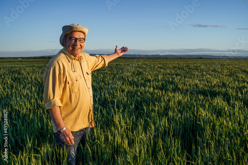 Senior farmer is standing in his growing wheat field. He is happy because of successful sowing. © djoronimo
