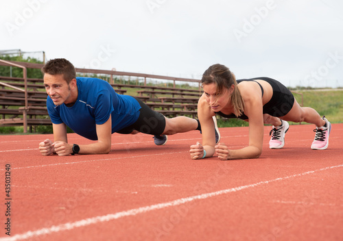 Sporty couple exercising on outdoor running track © Mati