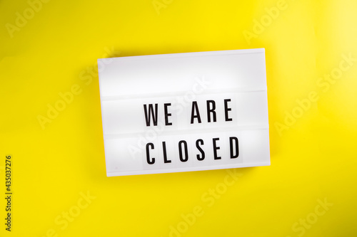 Lightbox with message WE ARE CLOSED isolated on yellow background. Concept of lockdown, business problems, holiday not working season, bankruptcy, liquidation, new normal, remote work, distance study