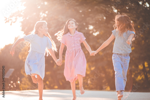 Three little girls running in nature together.