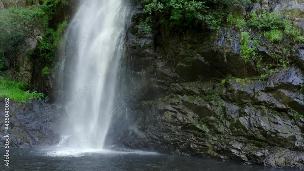 Beautiful landscape with a waterfall surrounded by green trees and jungle. Close up plan of tropical waterfall. Camera stands on the shore and we see how powerful jets of water fall into the lake. Beautiful landscape with a waterfall surrounded by green trees and jungle. Close up plan of tropical waterfall. Camera stands on the shore and we see how powerful jets of water fall into the lake.