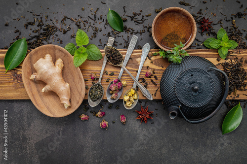  Black cast iron tea pot with herbal tea set up on dark stone background.