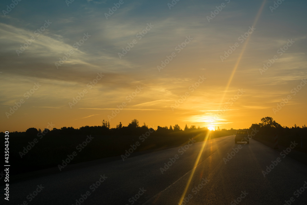Sunrise over road with traffic. Car silhouette. Orange sun. Sunrise over road with traffic. Car silhouette. Orange sun.