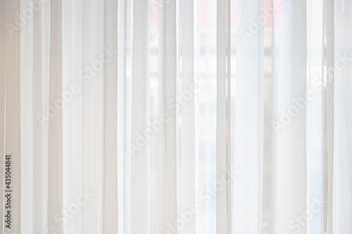 Light and see through concept  Classic white sheer curtains hanging by the window in the room with blurred view outside as background.