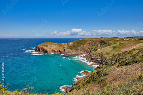 Image of Plemont Bay at high tide with blue sky and the headland. Jersey CI.