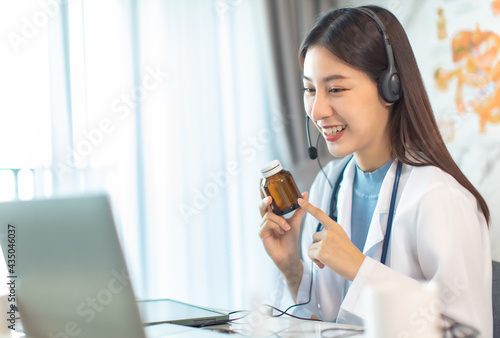 Portrait of young asian woman doctor with white coat standing in hospital.Telemedicine  Medical online  e health concept. Doctor using laptop for work.Remote medical help.