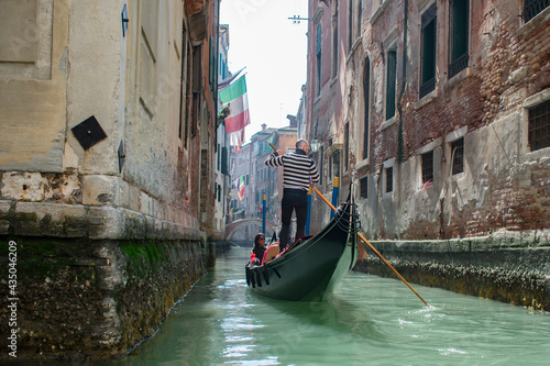 San Marco / Venice / Italy - April 17, 2019: Tourists in gondola ride in the historic city of Venice in Italy. Small canal