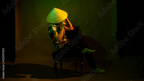 A guy in a plaid shirt and a Chinese hat on a dark background