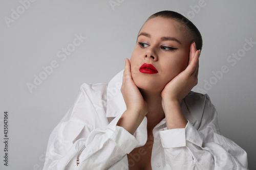 Young bald woman looking aside, posing in the studio. Isolated. photo