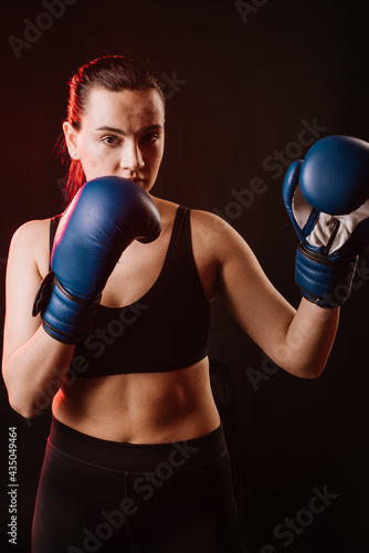 Sport woman boxer wearing blue boxing gloves on dark background © rostyslav84