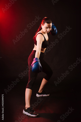 Sport woman boxer wearing blue boxing gloves on dark background