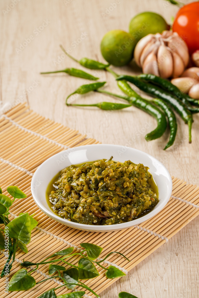 Sambal Lado Mudo or sambal Cabe Ijo. sambal cabe ijo is Traditional green chili paste from Padang, West Sumatra plated on plate and chili ingredient