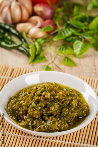 Close-up view of Sambal Lado Mudo or sambal Cabe Ijo. sambal cabe ijo is Traditional green chili paste from Padang, West Sumatra plated on plate and chili ingredient