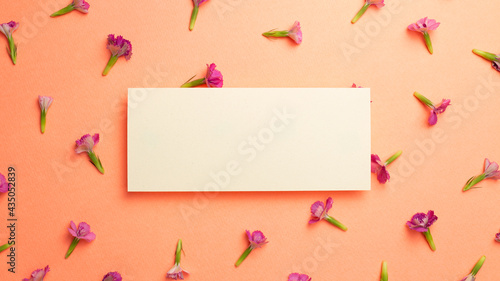 Memo pad with pink flower pattern on orange background. flat lay, top view, copy space