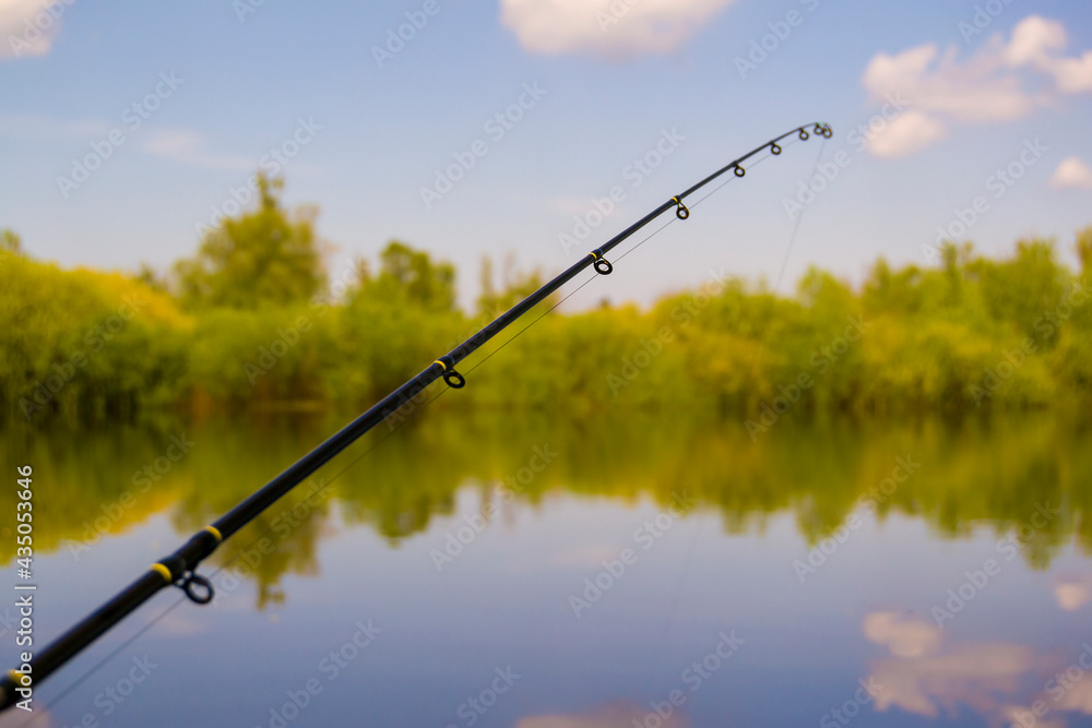 fishing rod with rings on the background of blue sky and river