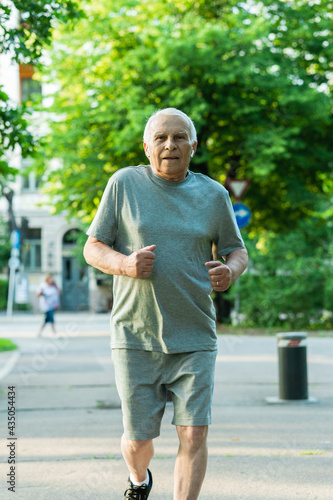 Fototapeta Naklejka Na Ścianę i Meble -  Elderly man during his jogging workout in a city park