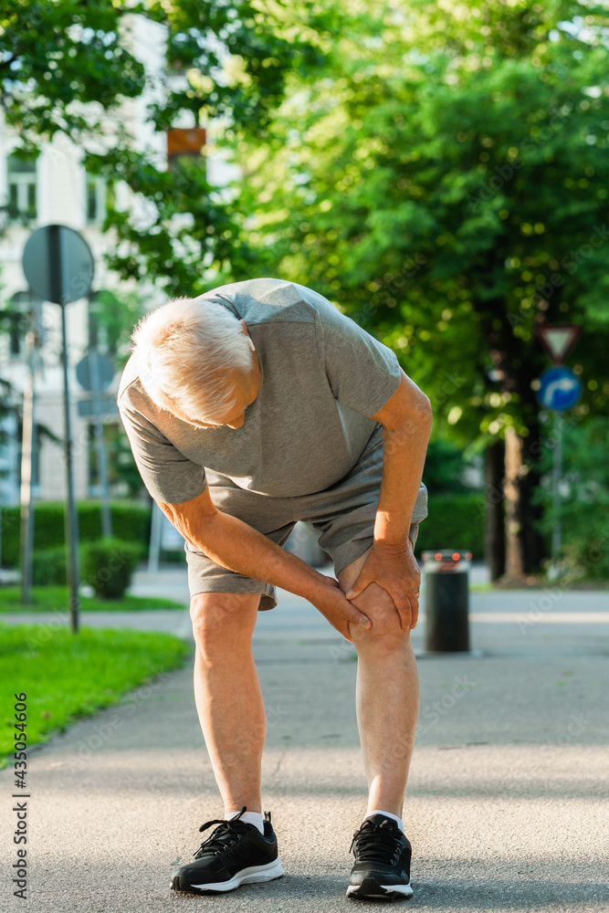 Elderly man suffering from knee pain during his jogging workout