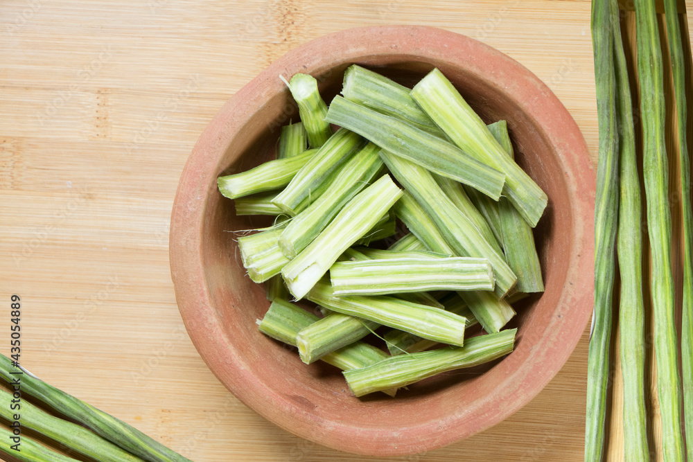 Drumstick vegetable chopped pieces in a bowl along with raw drumstick Drumstick vegetable chopped pieces in a bowl along with raw drumstick