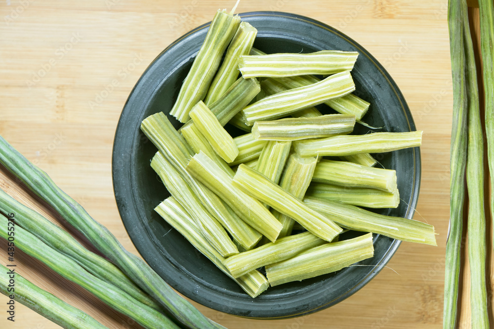 Drumstick vegetable chopped pieces in a bowl along with raw drumstick Drumstick vegetable chopped pieces in a bowl along with raw drumstick