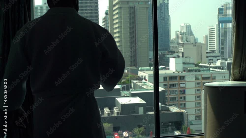 Man drinking and admire city view standing by window at home, slow motion Man drinking and admire city view standing by window at home, slow motion