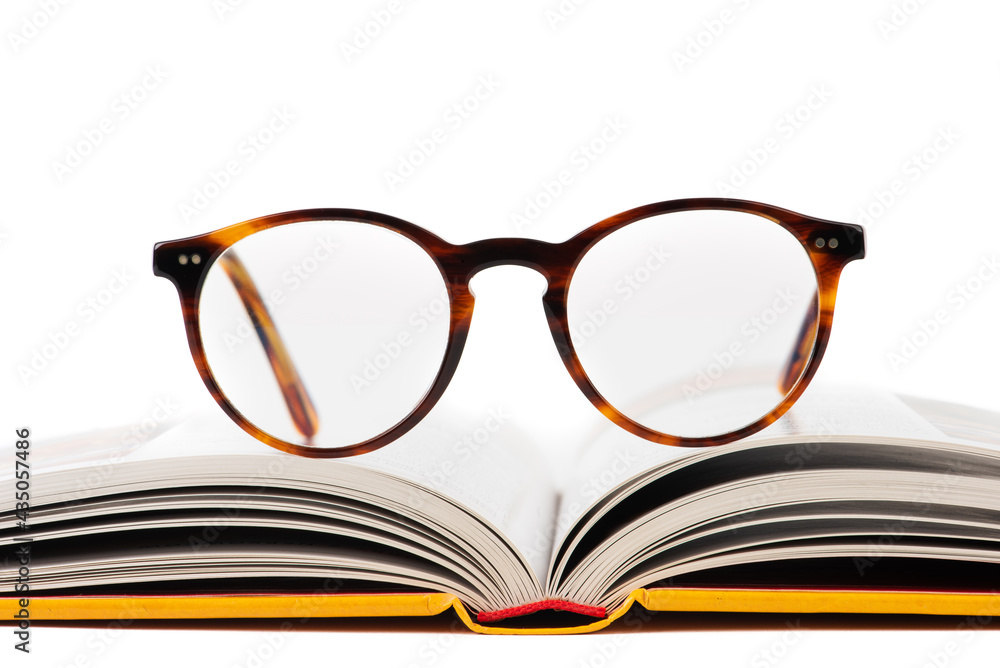 Close-up of opened book with reading glasses isolated on white background, front view Close-up of opened book with reading glasses isolated on white background, front view
