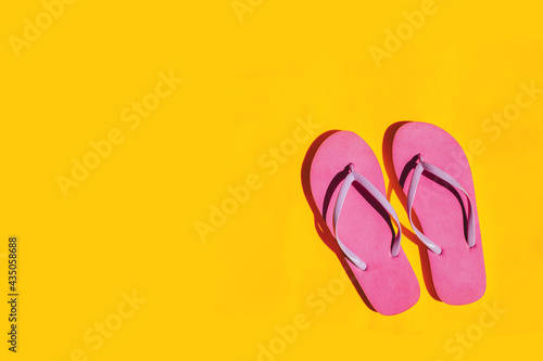 Pink flip flops on bright yellow background. Copy space.
