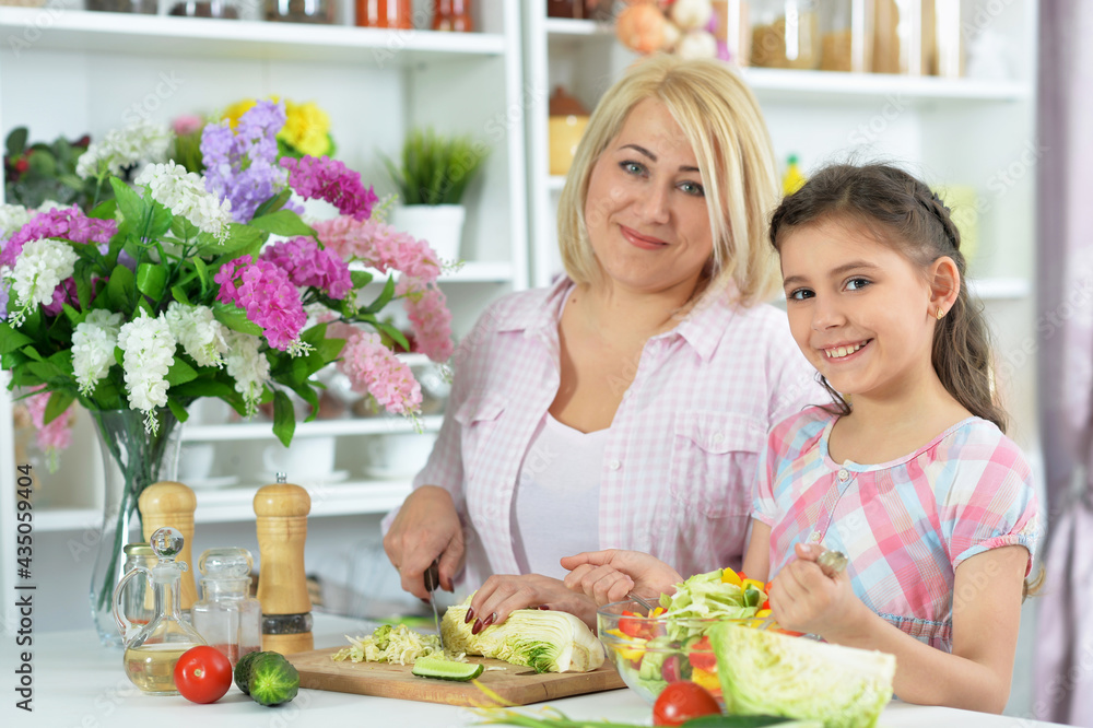 Happy mother and daughter cooking together at kitchen Happy mother and daughter cooking together at kitchen