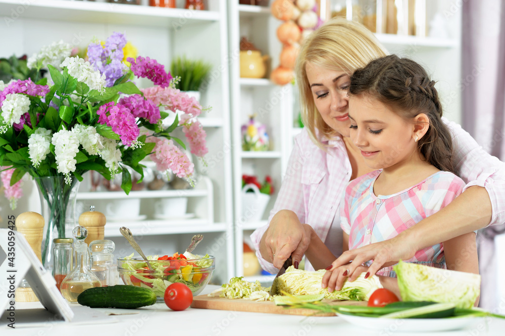 Cute little girl with her mother cooking together Cute little girl with her mother cooking together