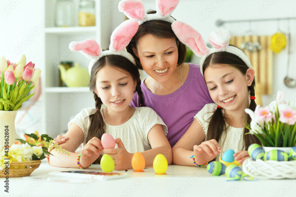 Cute twins with mother wearing rabbit ears decorating Easter eggs Cute twins with mother wearing rabbit ears decorating Easter eggs
