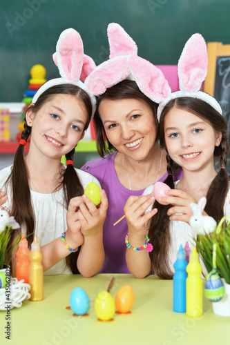 Cute twins with mother wearing rabbit ears decorating  Easter eggs