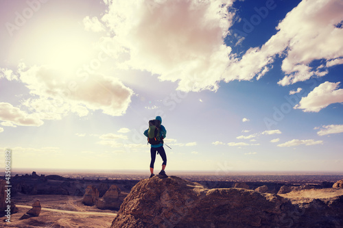 Successful backpacker standing on sandy hill top in desert